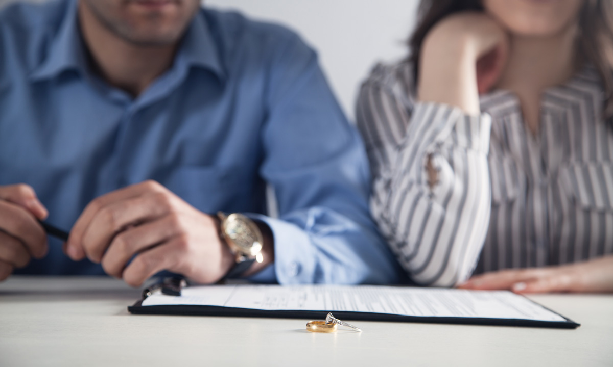 A couple seated next to each other with wedding rings and documents on the table in front of them in El Paso.