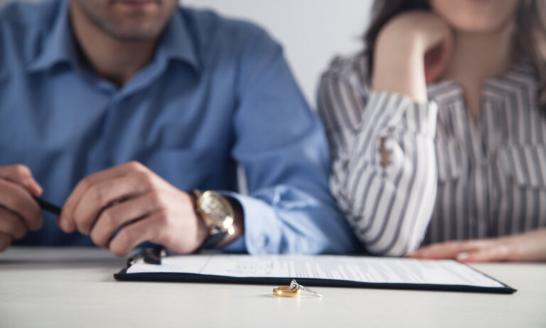 A couple seated next to each other with wedding rings and documents on the table in front of them in El Paso.