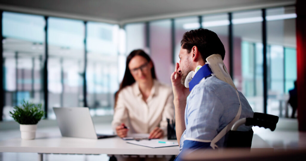 A man in a neck brace speaking to a personal injury attorney in an office in El Paso.